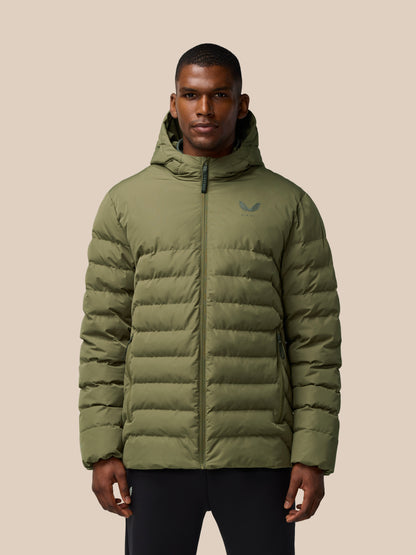 Man wearing ivy green lightweight puffer jacket with hood and front zipper, logo on chest, against a beige backdrop.