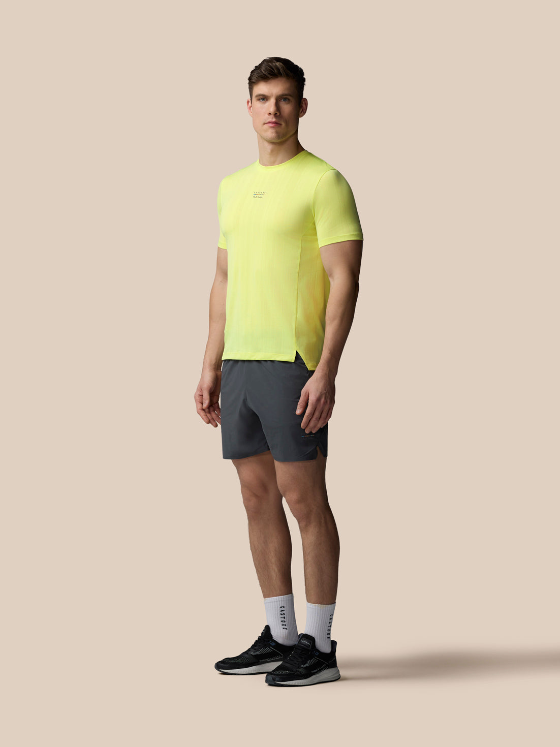 Full body shot of a male model in lime knit T shirt with dark shorts and black sneakers