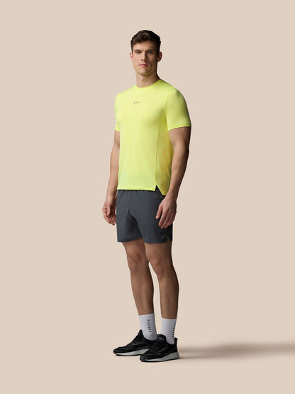 Full body shot of a male model in lime knit T shirt with dark shorts and black sneakers