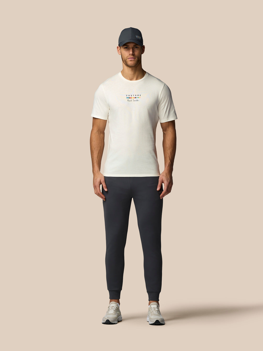 Man wearing a white t-shirt and dark pants on a beige background