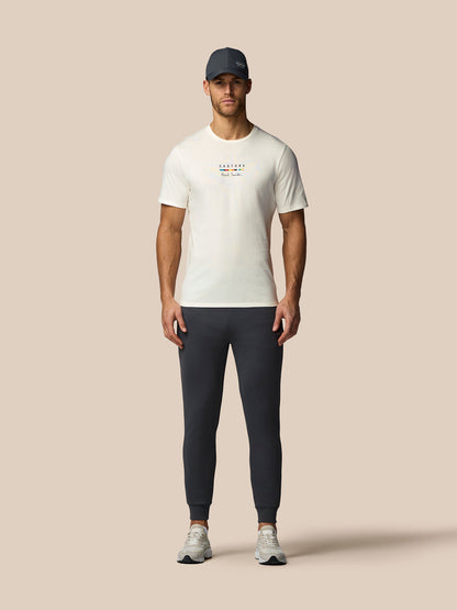 Man wearing a white t-shirt and dark pants on a beige background