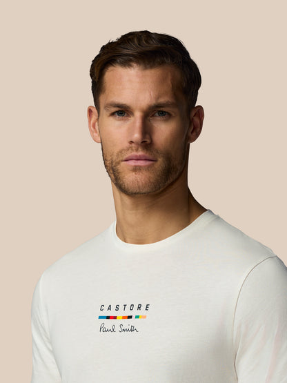 Man wearing a white t-shirt with 'Castore' and 'Paul Smith' logos on a beige background