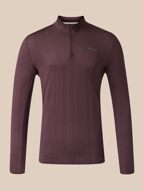 A long-sleeve quarter-zip athletic top shown from the front, in a dark plum-brown color with a small vertical multicolor logo near the upper back, set against a solid beige background.