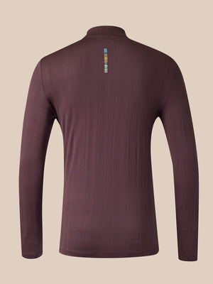 A long-sleeve quarter-zip athletic top shown from the back, in a dark plum-brown color with a small vertical multicolor logo near the upper back, set against a solid beige background.