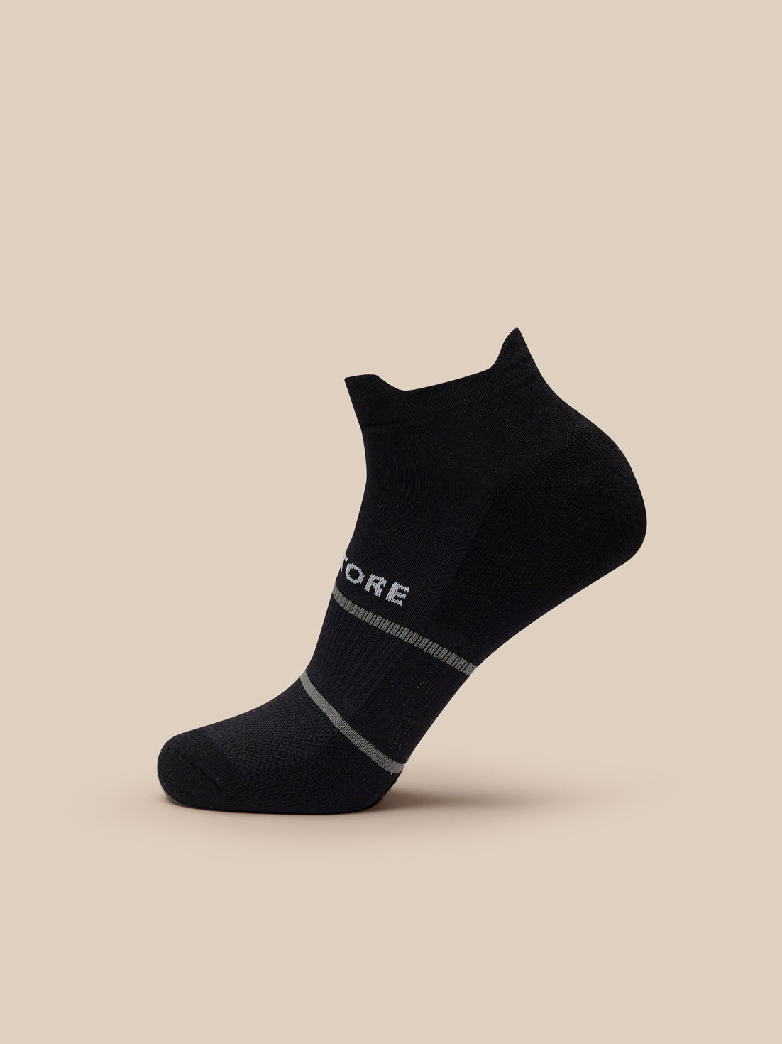 Single black ankle sock with a gray band and Castore logo against a beige background
