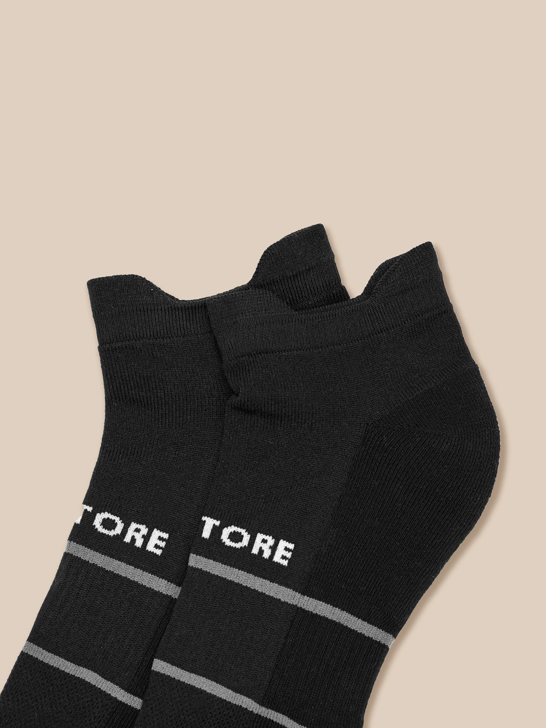 Close up of black ankle socks displaying Castore text and gray stripe patterns
