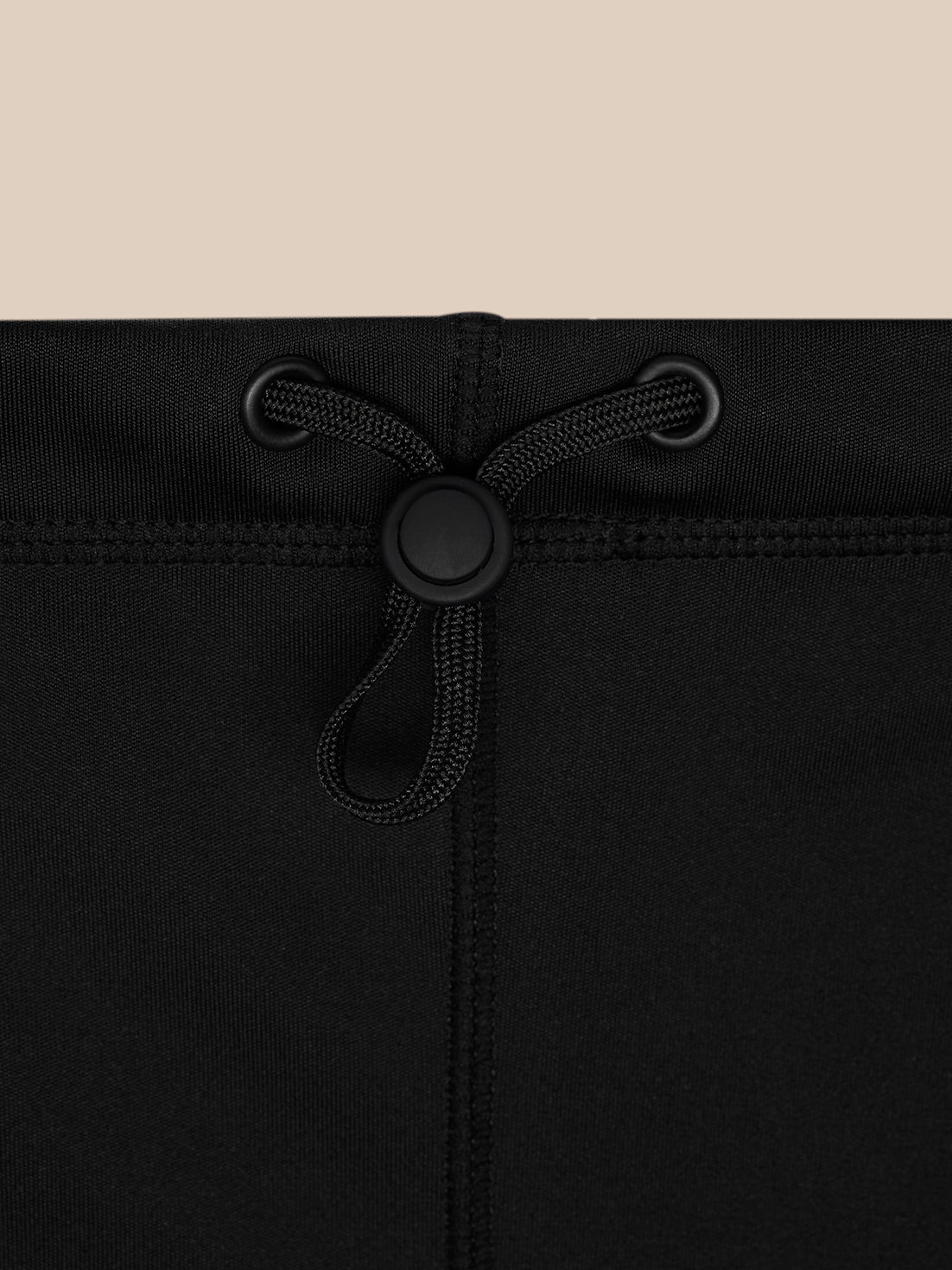 Close-up of black snood drawstring closure with a round plastic toggle and grommets.