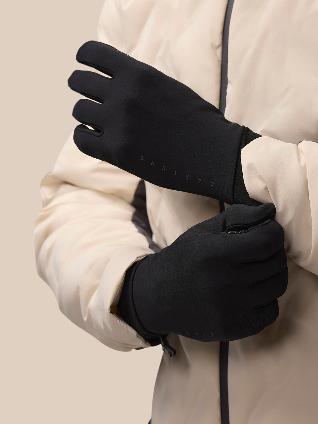 Model wearing black Pursuit glove with beige outer jacket, highlighting the wrist fastener