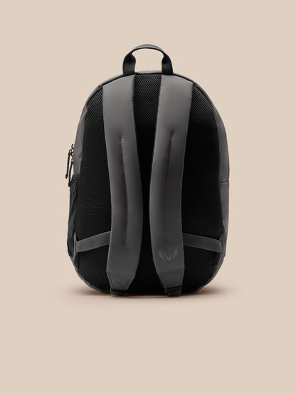Back view of a gunmetal Core Backpack showing padded shoulder straps, a top grab handle, and black mesh back panel.