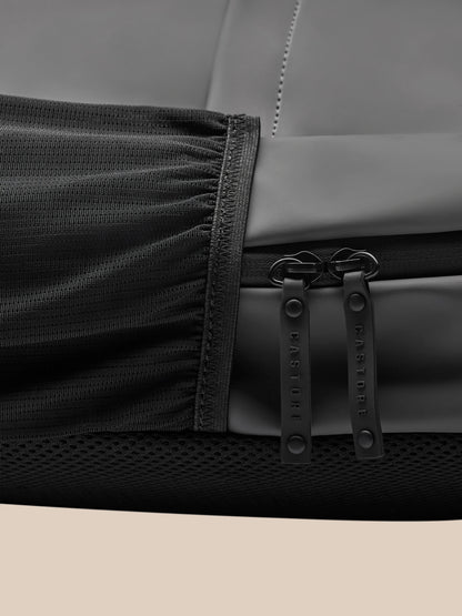 Close-up of gunmetal Core Backpack fabric with dual zipper pulls branded Castore and rugged edge stitching