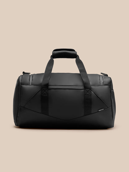 Black travel holdall with padded top handle and two wide straps shown against a beige background