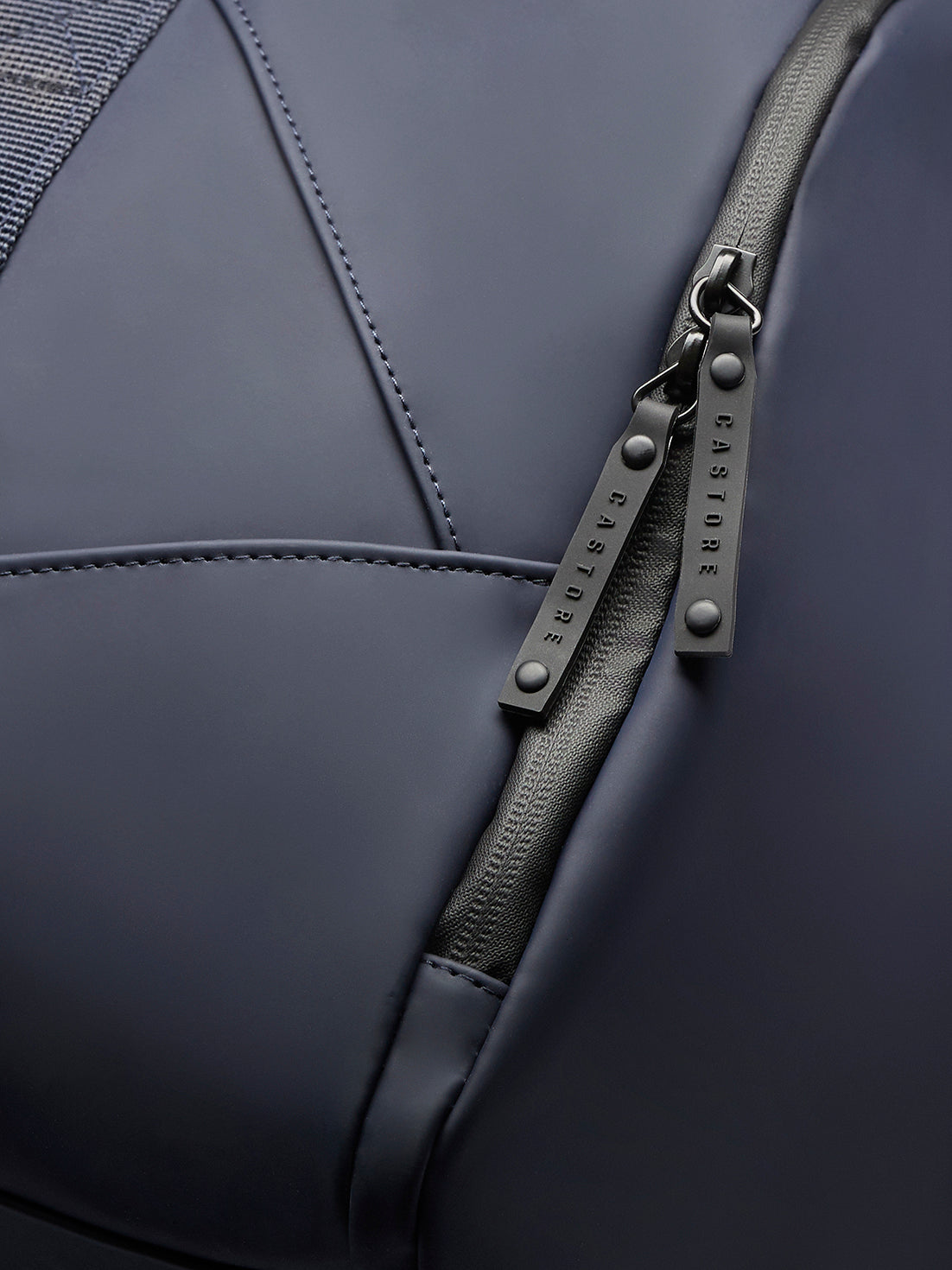 Detailed view of navy holdall zipper with double pulls and branded hardware on smooth fabric