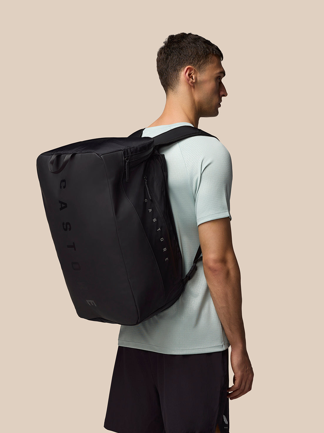 Male model wearing a black Pursuit Large Backpack with shoulder straps