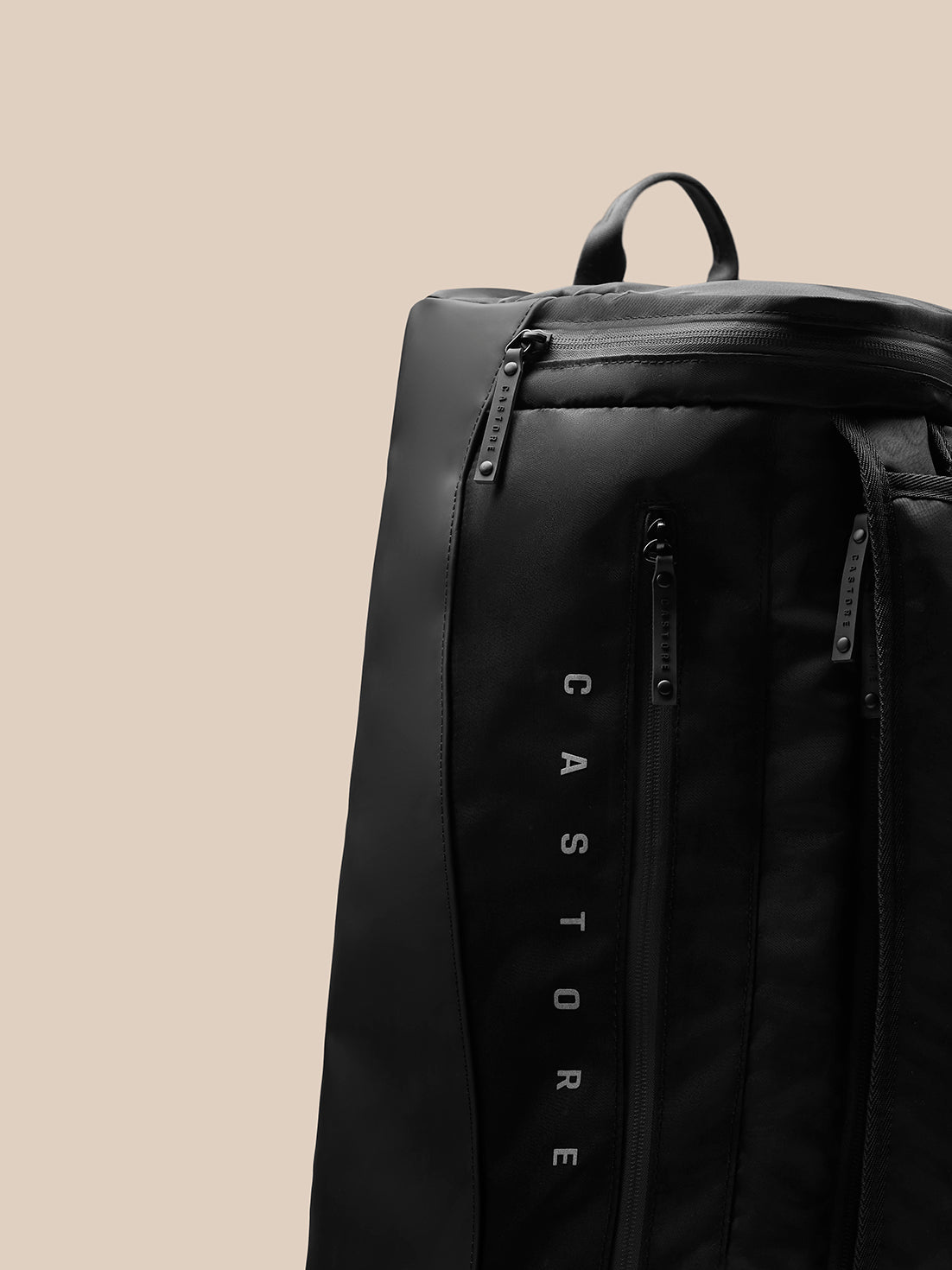 Close-up of black Pursuit Large Backpack highlighting vertical zipper and CASTORE branding on the strap
