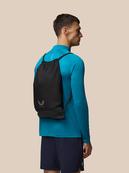 Model wearing black Castore Active Training Gymsack on back with blue athletic top