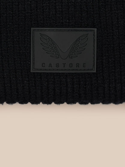 Close up of black ribbed Castore beanie with rectangular logo patch on front