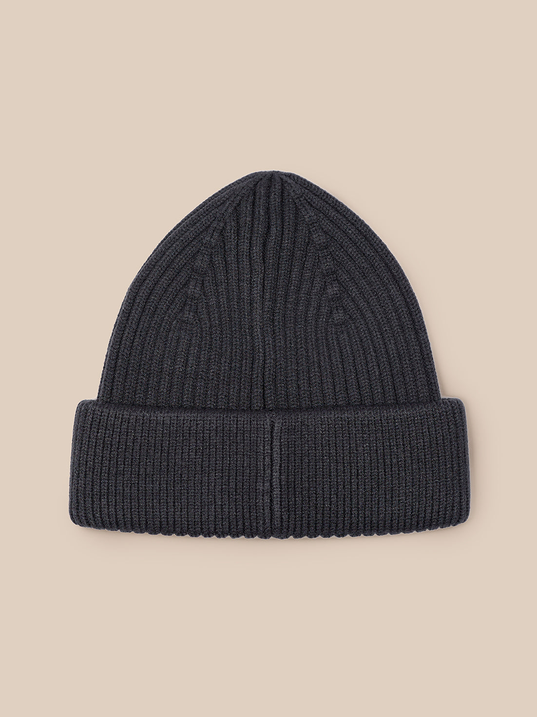 Close-up of dark grey ribbed knit beanie showing Castore logo patch on the cuff