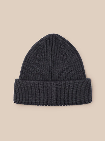 Close-up of dark grey ribbed knit beanie showing Castore logo patch on the cuff