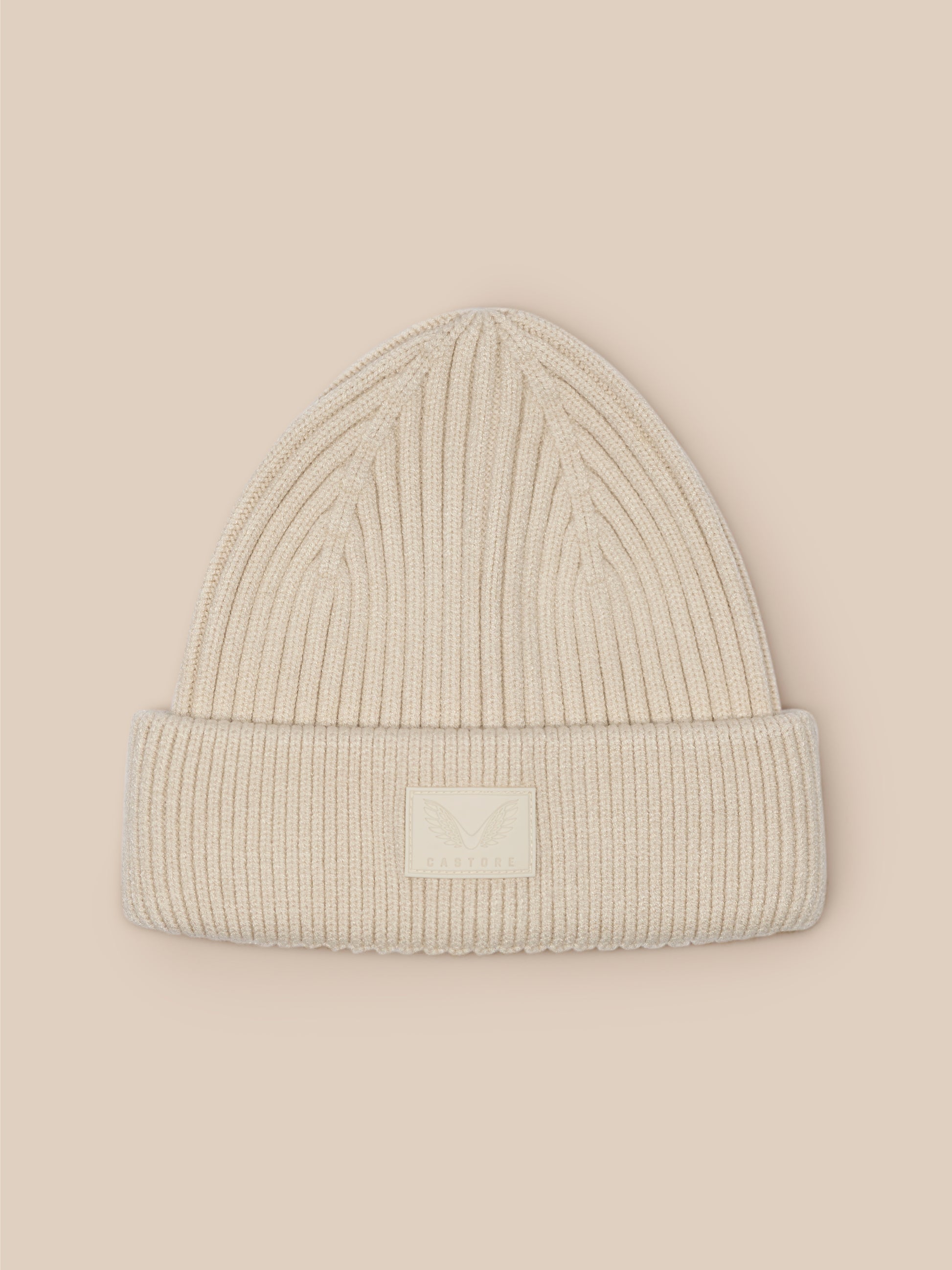 Stone colored ribbed knit beanie with a folded edge and Castore logo patch