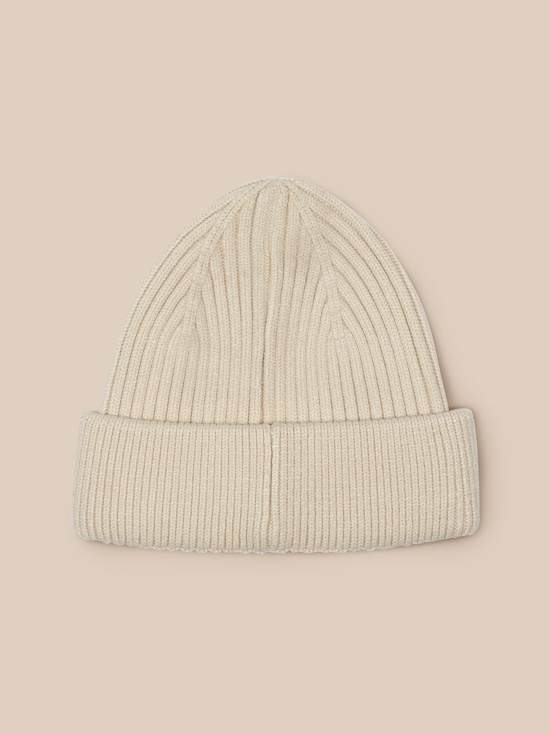 Beige ribbed beanie featured against neutral backdrop showing knit texture
