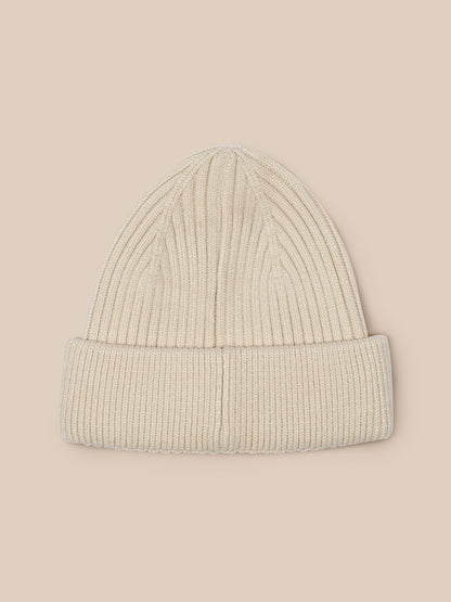Beige ribbed beanie featured against neutral backdrop showing knit texture