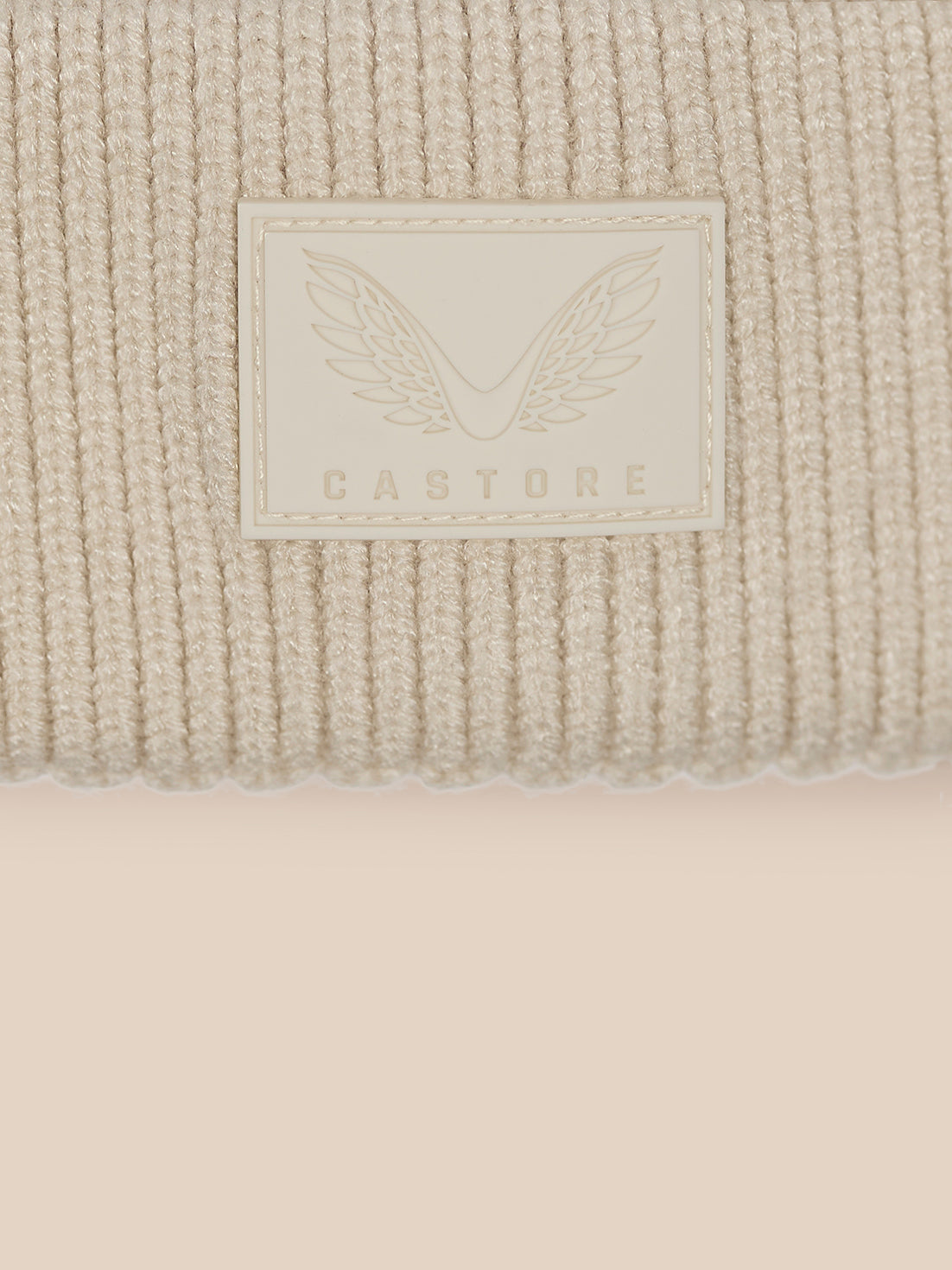 Close up of cuff showing Castore label with wings on beige knit