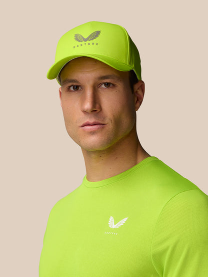 Three-quarter view of neon lime Castore Active Cap worn by a model in a lime shirt
