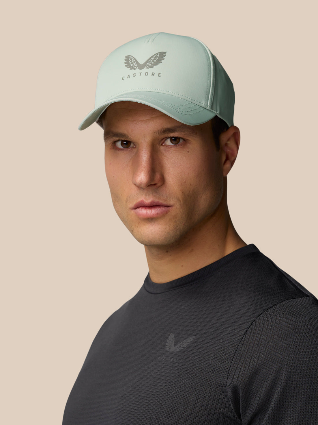 Model wearing a sage Unisex Active Logo Cap with the front Castore emblem.