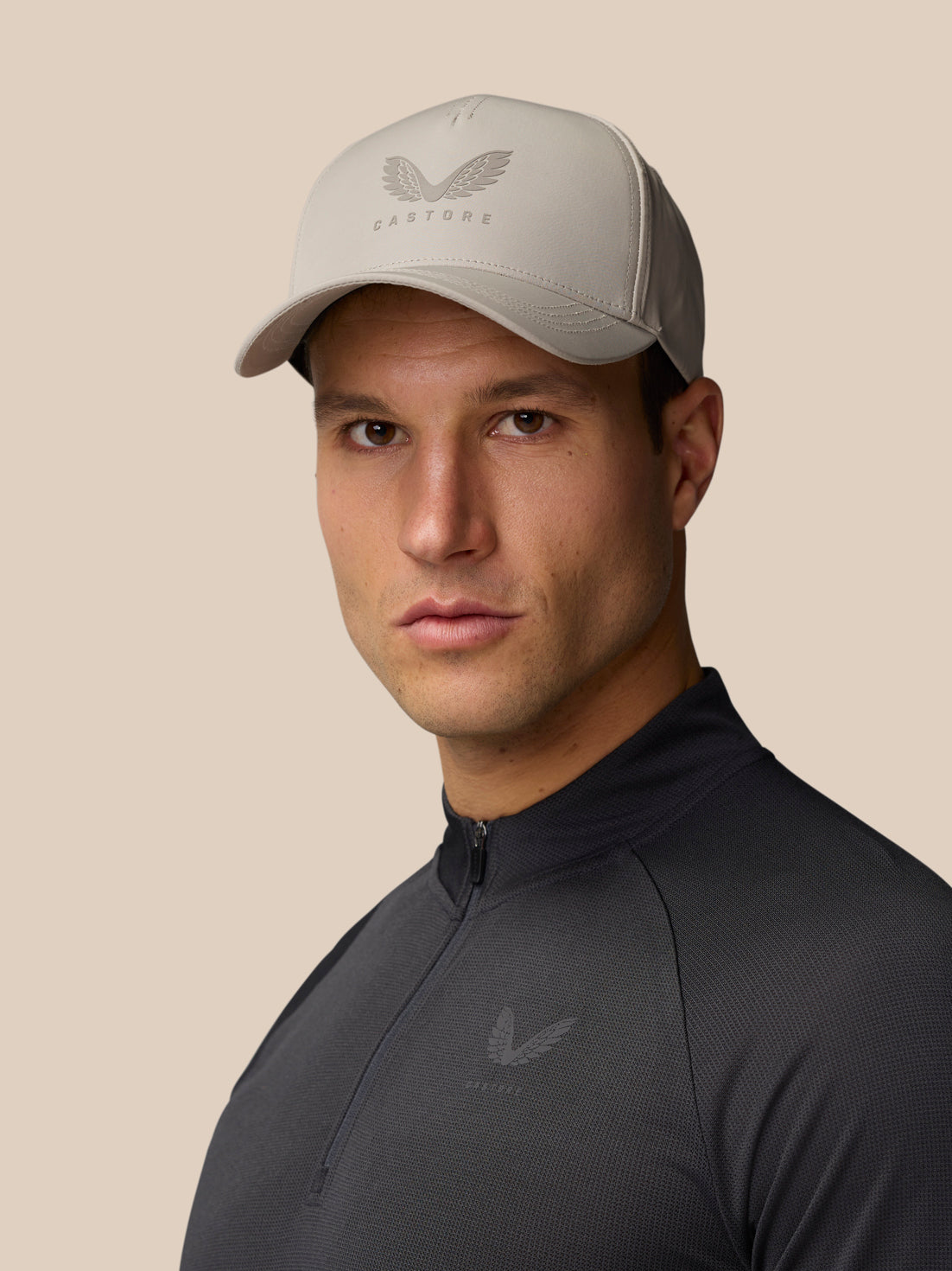 Back angle of Rock Grey Cap worn by a model in a dark athletic top with strap visible