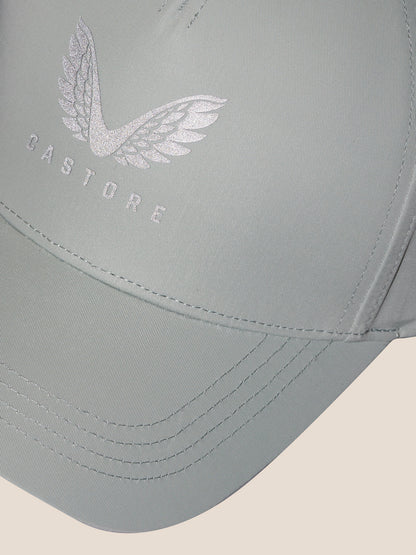 Close-up of the sage cap front displaying the embroidered Castore logo with wings.