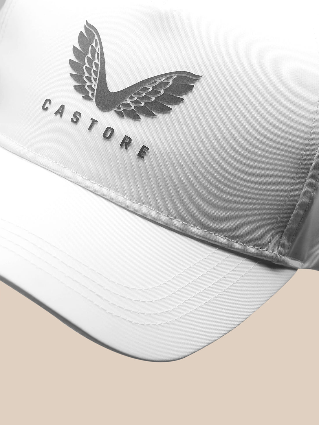 Close up of white Castore Core Cap front panel with winged logo and curved brim