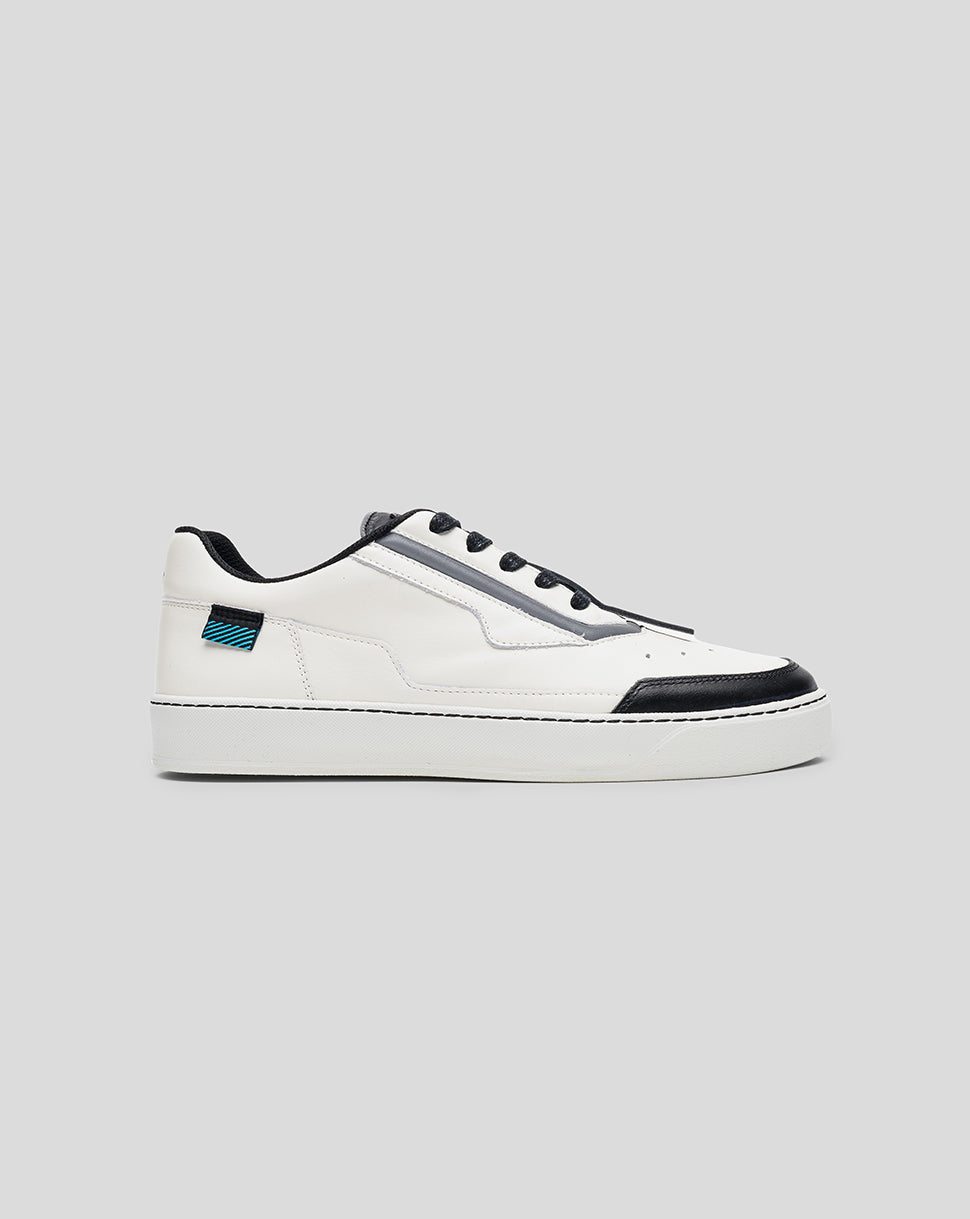 Profile view of white Endstate sneaker with black toe cap and blue striped heel patch.