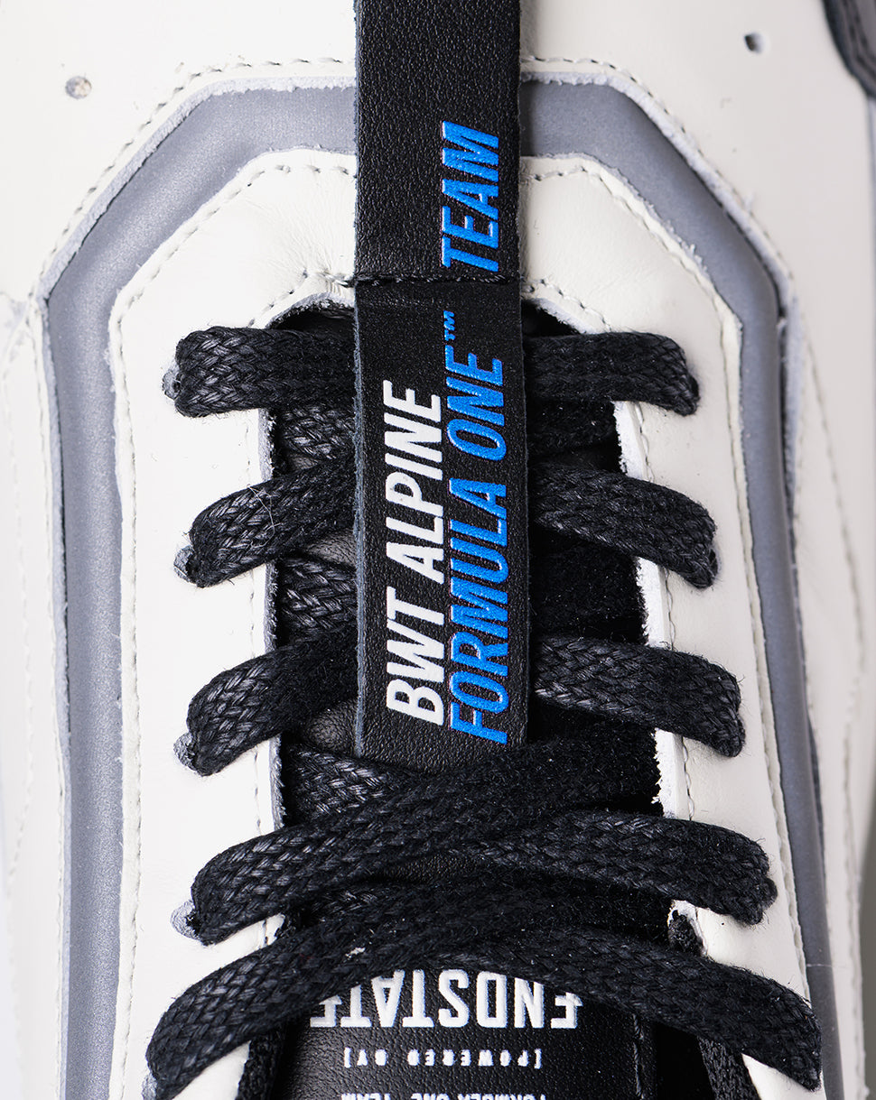 Close-up of tongue tag on white Endstate sneaker featuring BWT Alpine Formula One Team branding.