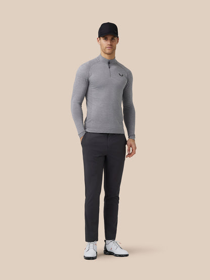 Full-length shot of a male model wearing a grey golf top, dark trousers, cap and white shoes