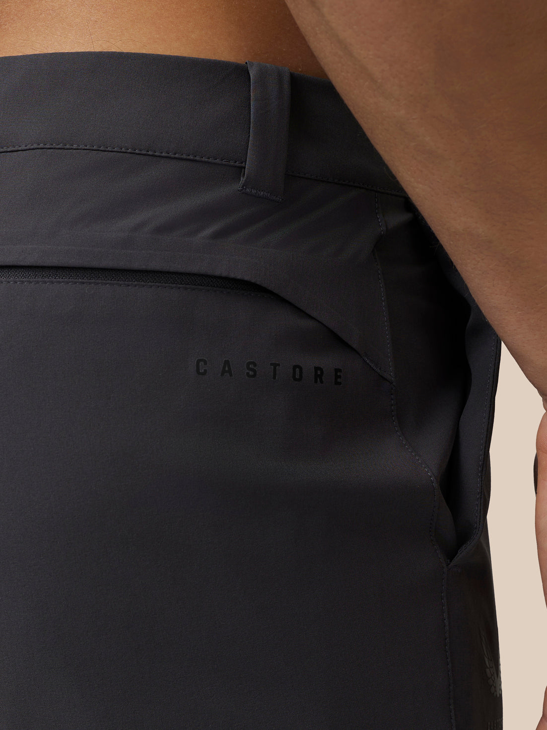 Back view close-up of grey golf trousers showing a welt back pocket and Castore branding