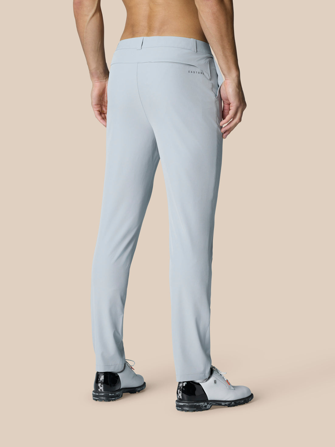 Back view of a man wearing light grey golf trousers showing back pocket and Castore branding.