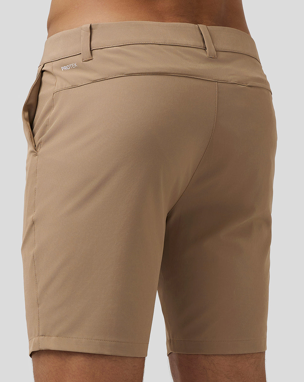Male model wearing clay colored golf shorts with a matching polo in a full body pose.