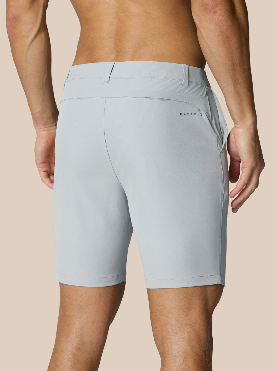 Back view of a man wearing light grey golf shorts with belt-loop waistband and Castore branding on the right thigh and rear.