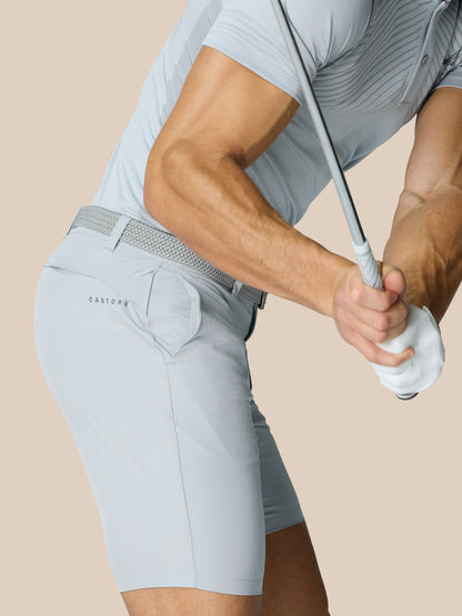Side view of a man wearing light grey golf shorts with braided belt and Castore branding at the rear.