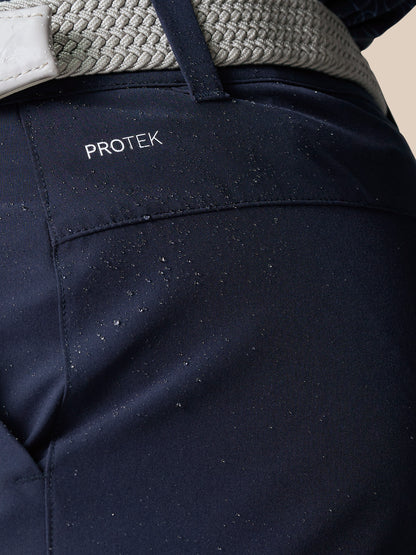 Close up of navy golf shorts fabric with visible ProTek branding and water droplets