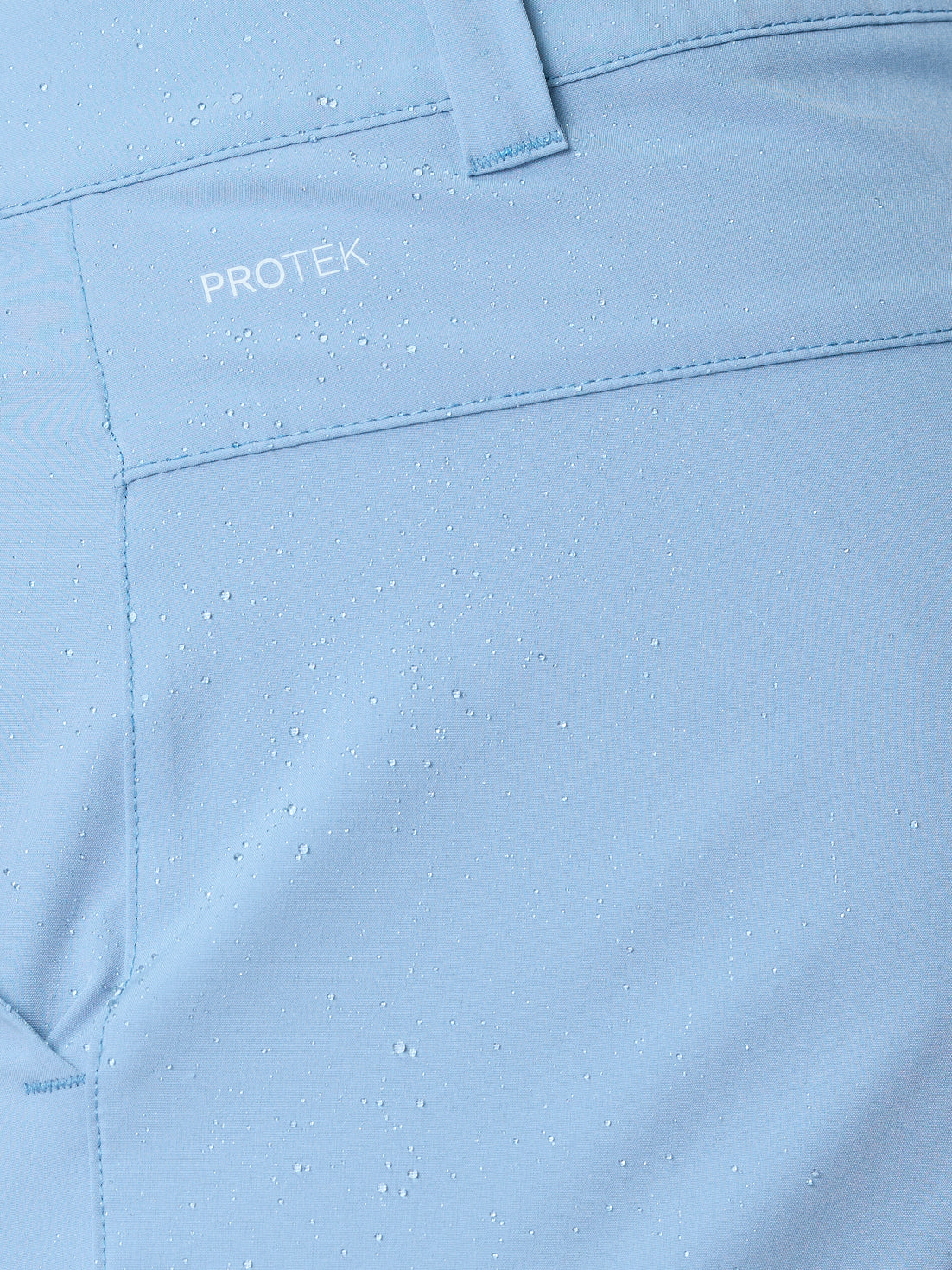 Close-up of sky blue Golf Club Shorts fabric with water droplets to highlight ProTek water resistance