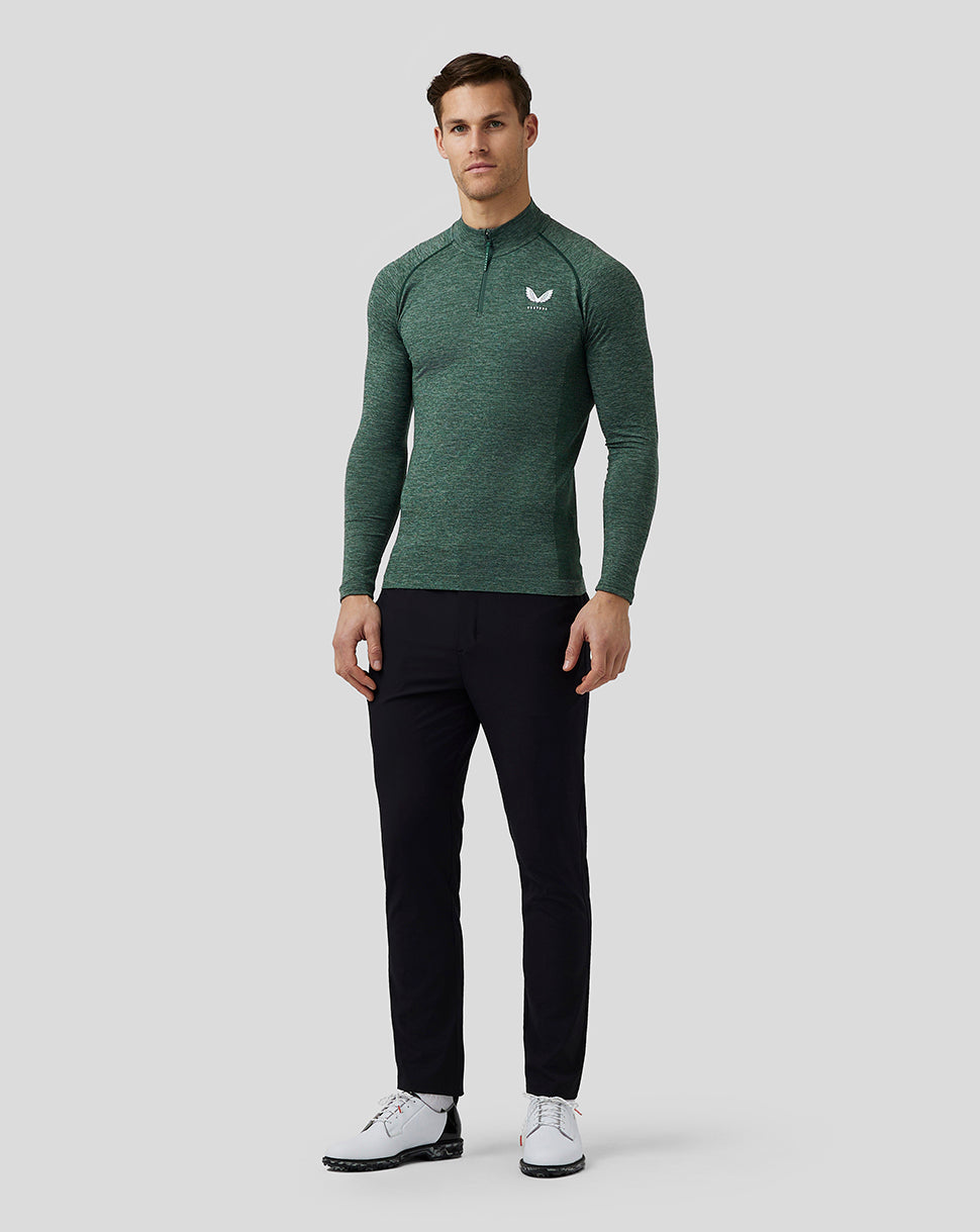 Front view of male model wearing pine grey body mapped seamless quarter zip top with stand collar and Castore logo on the left chest, paired with black pants.