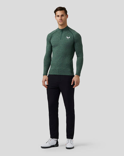 Front view of male model wearing pine grey body mapped seamless quarter zip top with stand collar and Castore logo on the left chest, paired with black pants.