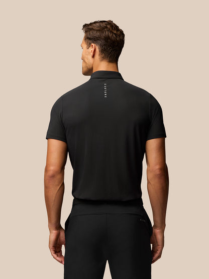 Back view of a man wearing a black Golf Club Essential Polo with Castore branding down the upper back.