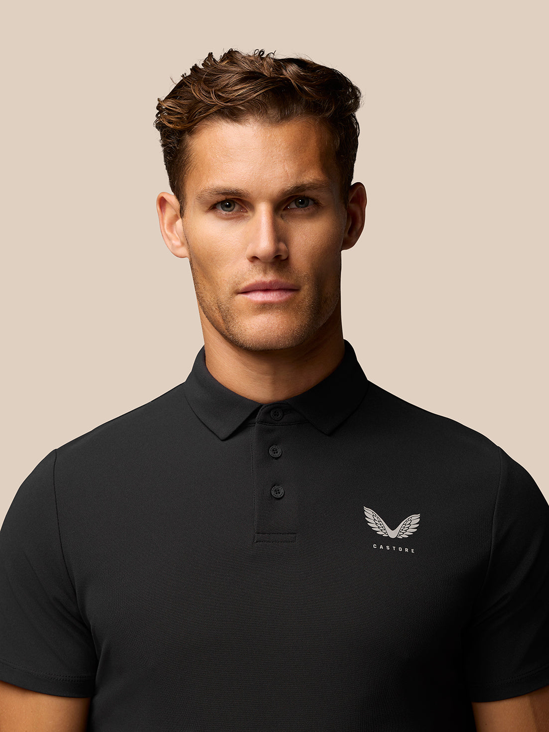 Male model wearing black Golf Club Essential Polo with Castore logo on left chest.