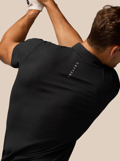 Back view of a man in a black Golf Club Essential Polo with vertical Castore branding along the upper back.