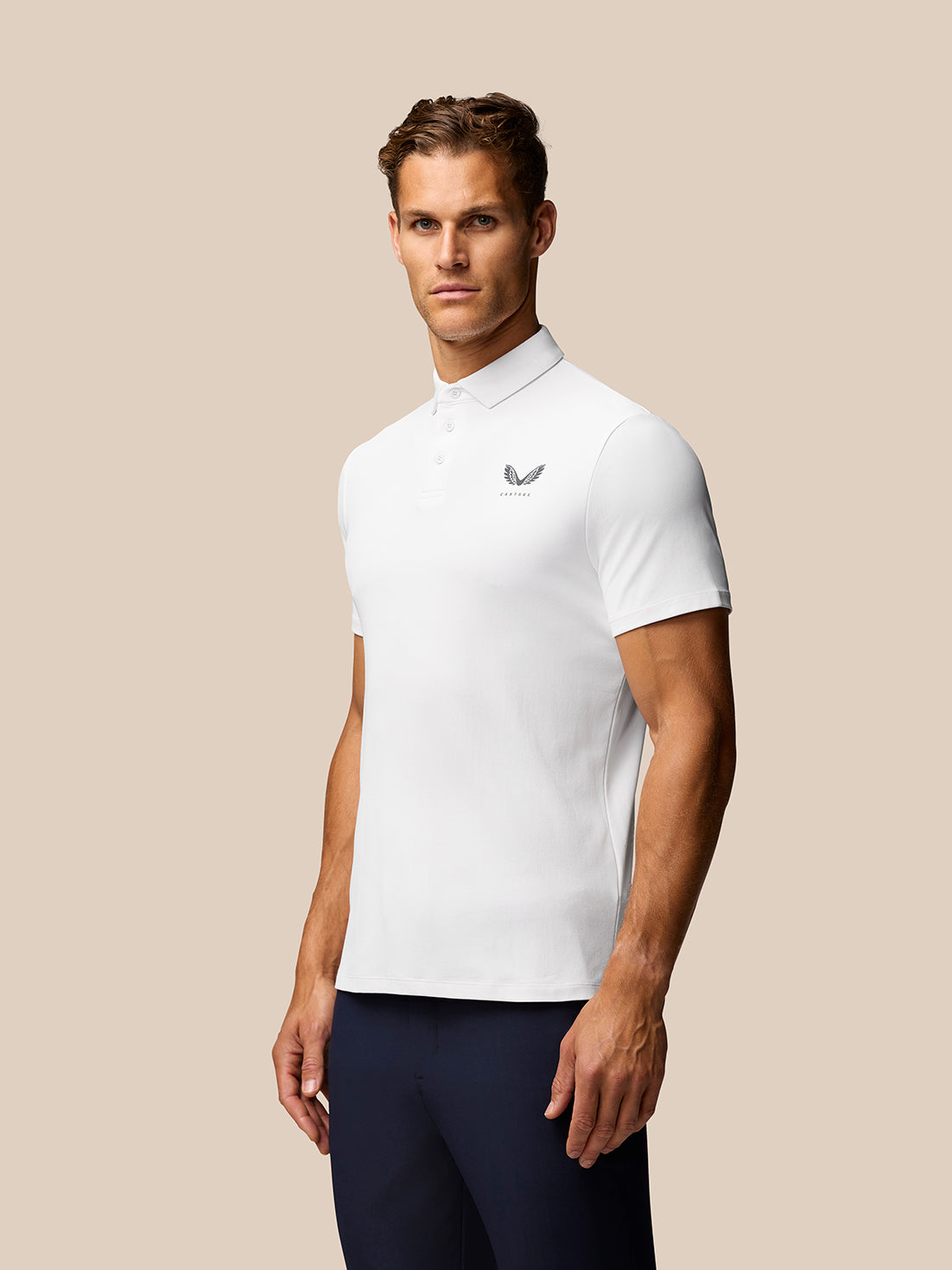 Male model wearing white Golf Club Essential Polo with pointed collar and three-button placket; Castore branding on chest
