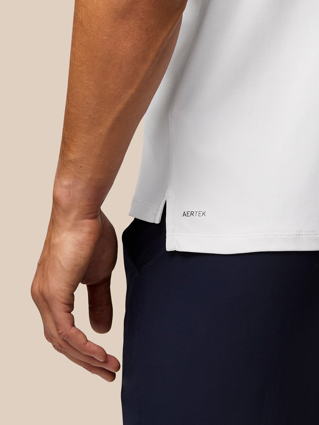 Close-up of the polo hem and sleeve on a white golf shirt, showing the AERTEK branding.