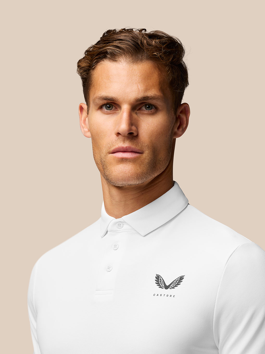 Close-up of the white golf polo upper torso with collar and left chest Castore logo.