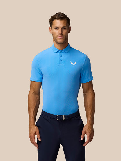 Torso-up view of male model wearing cool blue Golf Club Essential Polo with Castore logo on chest.